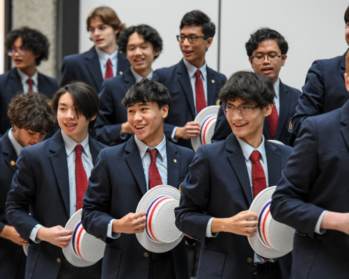 St. Michaels Choir, group of boys dressed in suits and holding white hats in their hands while singing.