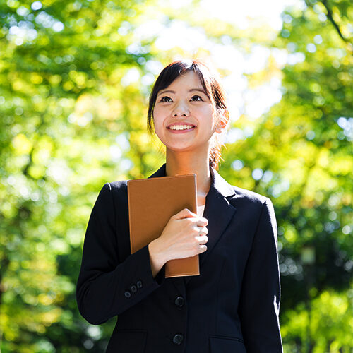 Decorative image of a smiling business woman in a dark suit holding a large notebook.