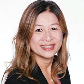 Portrait of Mable Wakamatsu who has brown hair with blonde highlgihts. Mable is wearing a black blazer with a pink blouse.