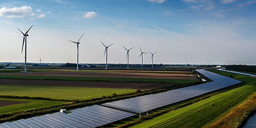 Decorative image of flat agricultural land with a riverlike row of solar panels and a row of wind turbines in the background.