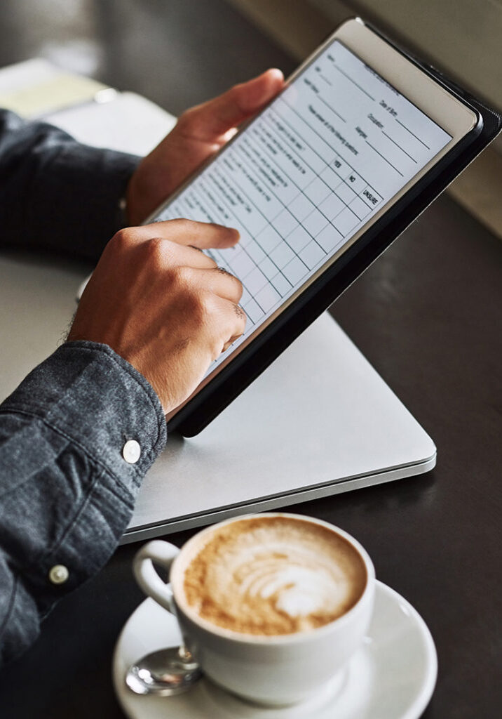 Image of a man using a tablet with a cappuccino ready for the first sip