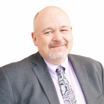 Portrait of Scott Rees in a grey jacket and patterned tie