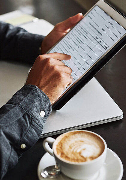 Image of a man using a tablet with a cappuccino ready for the first sip